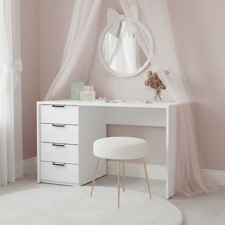 Białe biurko Barold o wymiarach 120x60 cm w aranżacji toaletki w jasnej sypialni. Nad blatem wisi okrągłe lustro z kokardą, a na biurku stoją kosmetyki i wazon z kwiatami, tworząc elegancką przestrzeń do makijażu.