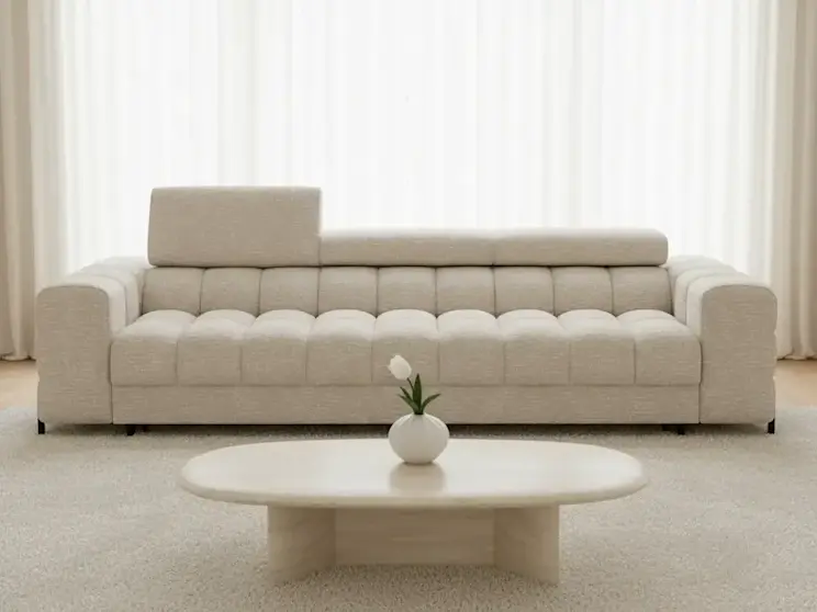 Beżowa kanapa Festello Baffix 20 z pikowanym siedziskiem ustawiona w jasnym salonie z zasłonami, okrągłym stolikiem kawowym i minimalistyczną dekoracją.