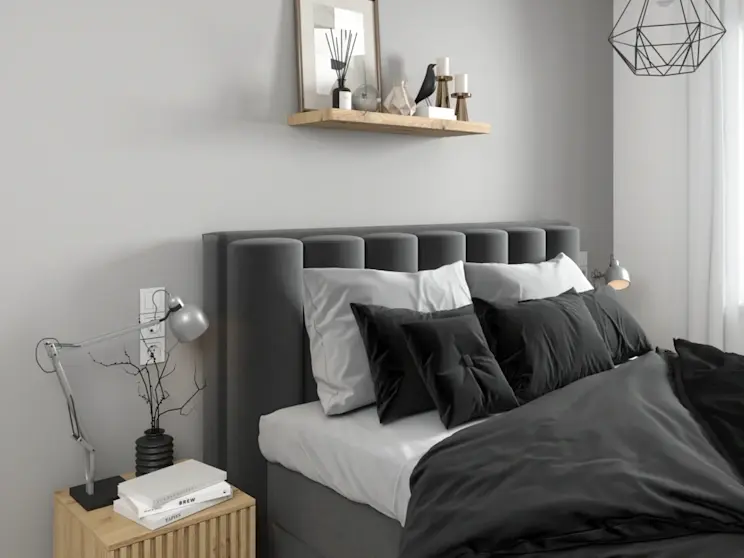 Aranżacja sypialni w szarościach z łóżkiem Veros Flores 10 oraz drewnianym stolikiem nocnym Entsian. Na ścianie zawieszona półka Garris z ramką i świecami, a oświetlenie zapewnia lampa Benigne II i minimalistyczne lampki nocne.