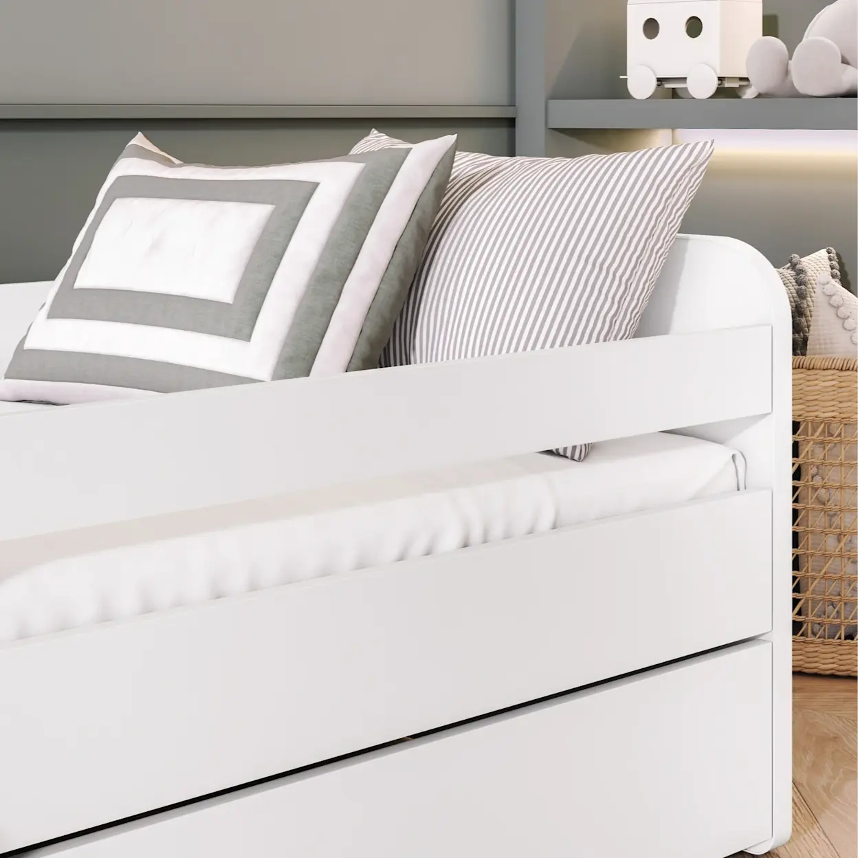 Zbliżenie na białe łóżko dziecięce Duuli z materacem, z widoczną barierką zabezpieczającą i miękkim posłaniem. Jasna kolorystyka oraz poduszki tworzą spokojną, przytulną przestrzeń do snu.