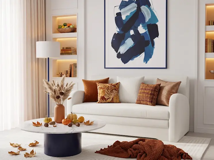 Biała sofa Ario w tkaninie boucle Royal 01, zaprezentowana w eleganckim salonie z granatowymi dodatkami i nowoczesną sztuką na ścianie.
