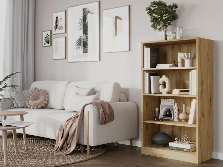 Przytulne wnętrze z kanapą Arcadova w tkaninie Jaffray 01 i regałem Pocett na książki oraz ozdoby. Neutralne kolory, naturalne materiały i uporządkowane półki tworzą harmonijną przestrzeń do odpoczynku w salonie.