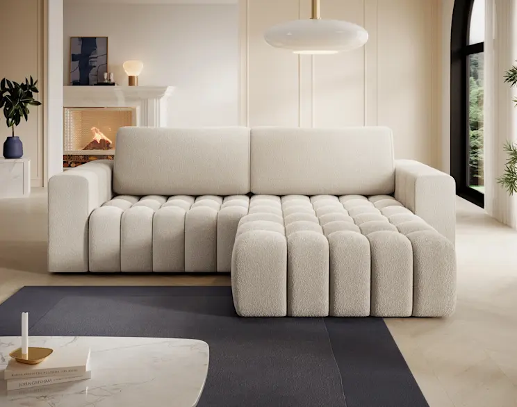 Jasny narożnik Bonett Jaffray 18 z szezlongiem, tapicerowany tkaniną typu bouclé, w eleganckim salonie z kominkiem.