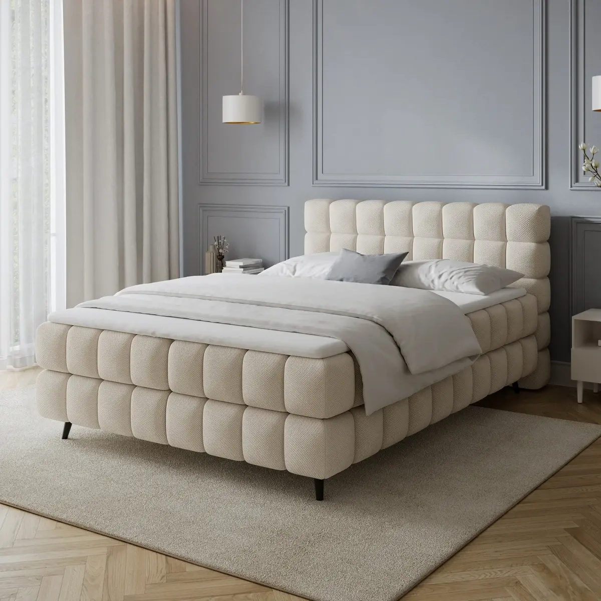 Łóżko kontynentalne Sabeno w tkaninie Calmora 18 w jasnej sypialni z szarą ścianą, dużymi oknami i minimalistycznymi dodatkami.