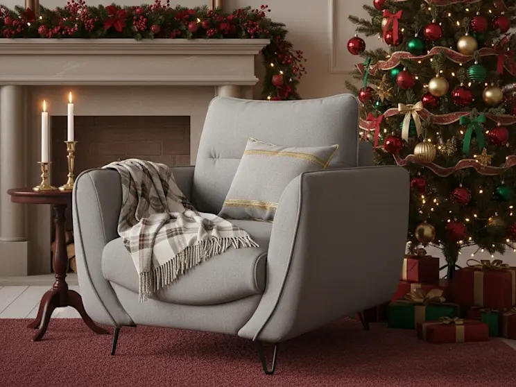 Fotel Silva Gojo 02 w jasnej tkaninie ustawiony obok kominka i choinki, otoczony świątecznymi dekoracjami w czerwieni i złocie, tworzy ciepły klimat wnętrza.