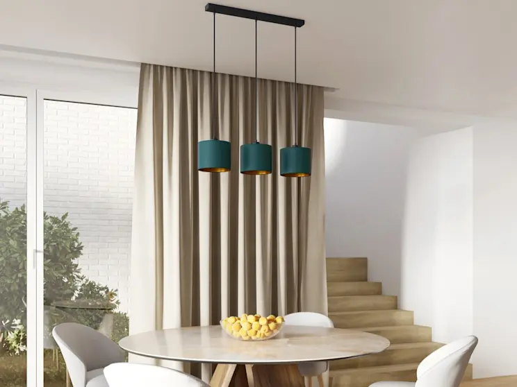 Lampa liniowa Vespillo – trzy zielone zwisy nad stołem, jasna jadalnia z drewnianą podłogą.