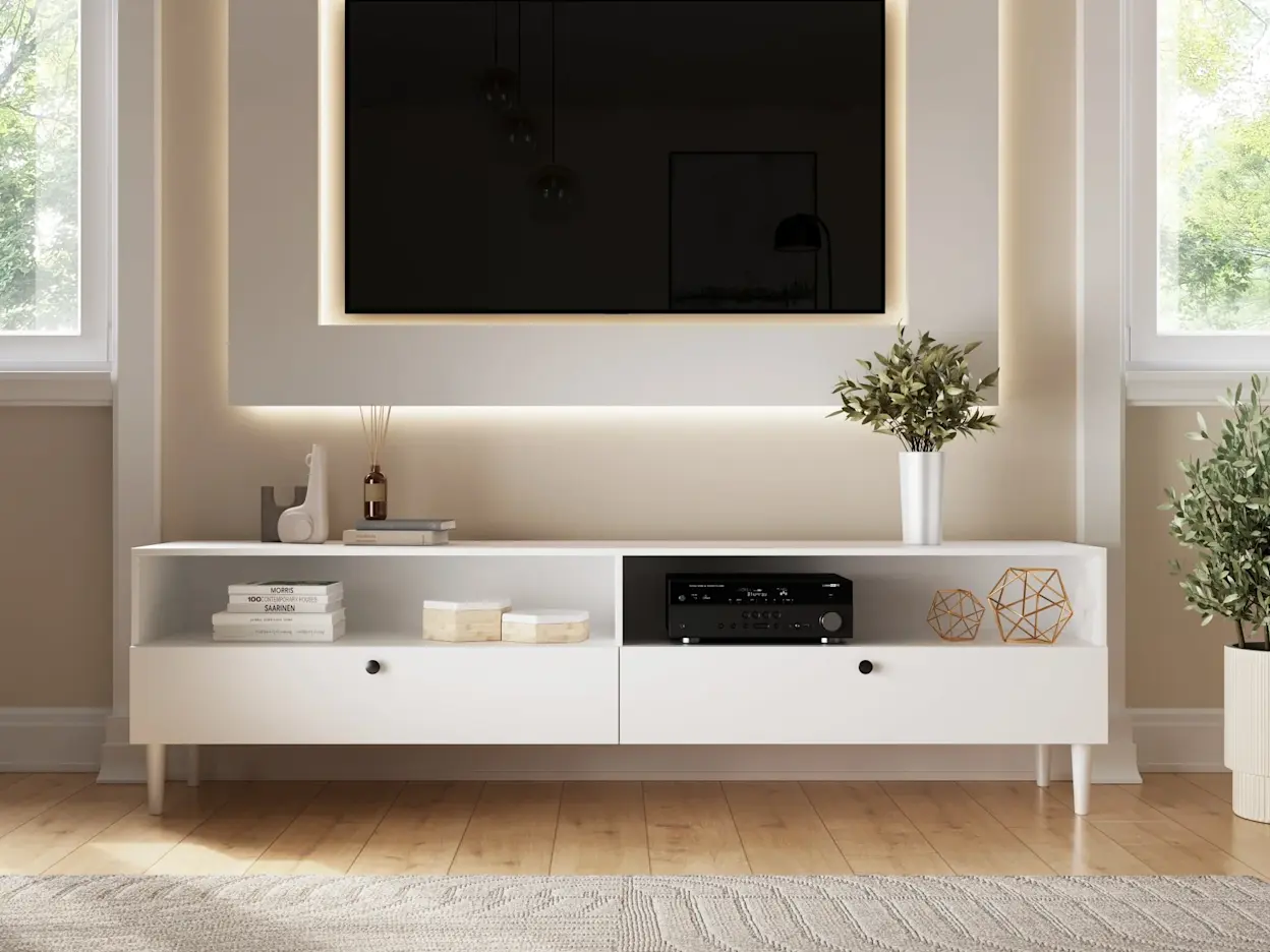 Minimalistyczna szafka RTV Dullum w bieli, ozdobiona książkami i dekoracjami, w eleganckim wnętrzu z ciepłym oświetleniem.