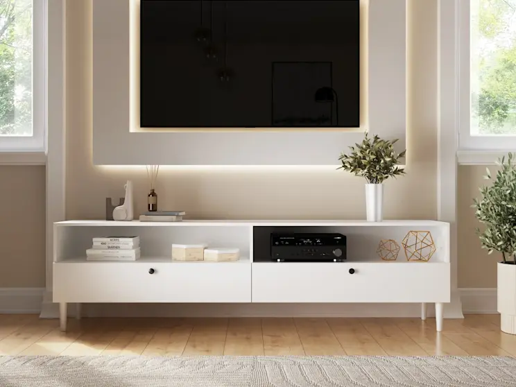 Minimalistyczna szafka RTV Dullum w bieli, ozdobiona książkami i dekoracjami, w eleganckim wnętrzu z ciepłym oświetleniem.