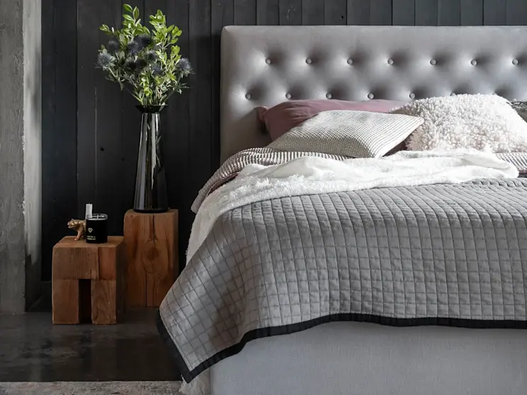 Tapicerowane łóżko kontynentalne Loree z praktycznym pojemnikiem na pościel. Miękkie wezgłowie i stonowana kolorystyka sprzyjają relaksowi.