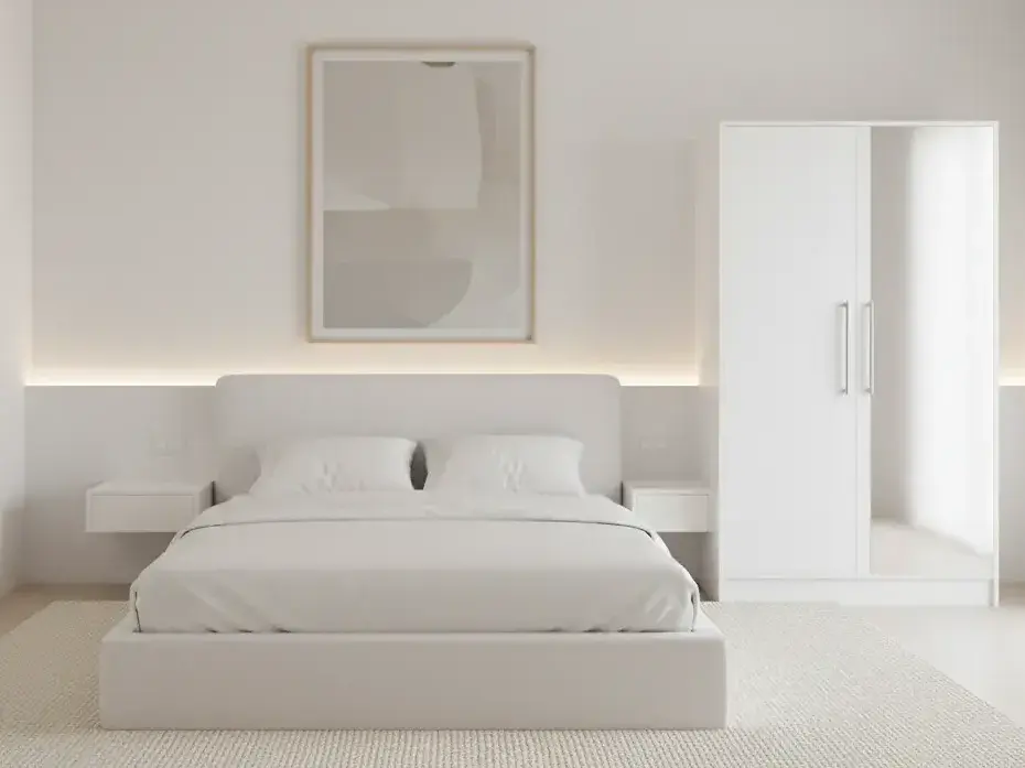 Szafa Alarica II w kolorze białym z lustrem ustawiona w nowoczesnej sypialni z miękkim dywanem, prostymi szafkami nocnymi i delikatnym oświetleniem. Funkcjonalne lustro podkreśla przestronność i jasny charakter wnętrza.