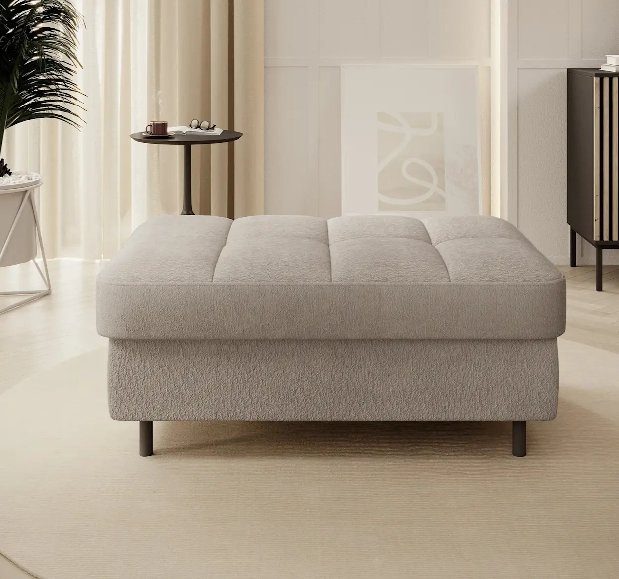 Tapicerowana pufa Gomsi Touch 18 w odcieniu beżowym na czarnych nogach, ustawiona w eleganckim, jasnym salonie z naturalnym światłem.