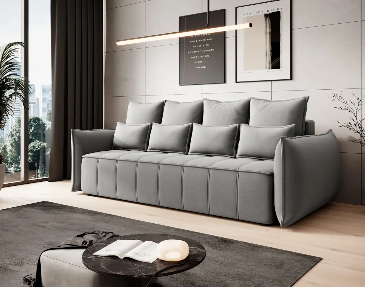 Nowoczesna kanapa Wellton w szarym kolorze z poduszkami oparciowymi, w eleganckim salonie z grafikami na ścianie i dywanem.