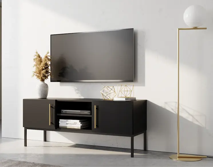 Czarna szafka RTV Lanzzi z eleganckimi złotymi uchwytami, ustawiona pod telewizorem w nowoczesnym, jasnym salonie z designerską lampą.