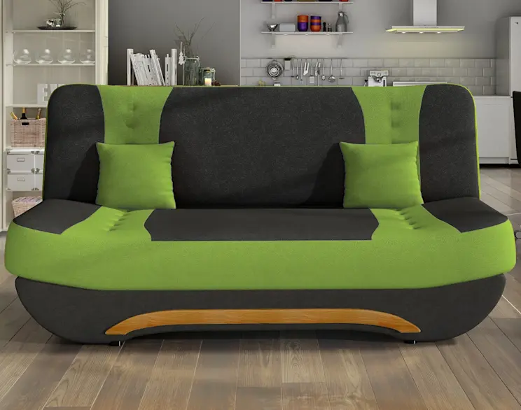 Kanapa Ewa II w tapicerce Alova 04/Alova 4 – zielono-grafitowa sofa z zaokrąglonym oparciem i dwiema zielonymi poduszkami. Na dole widoczny dekor drewniany, w tle jasny aneks kuchenny.