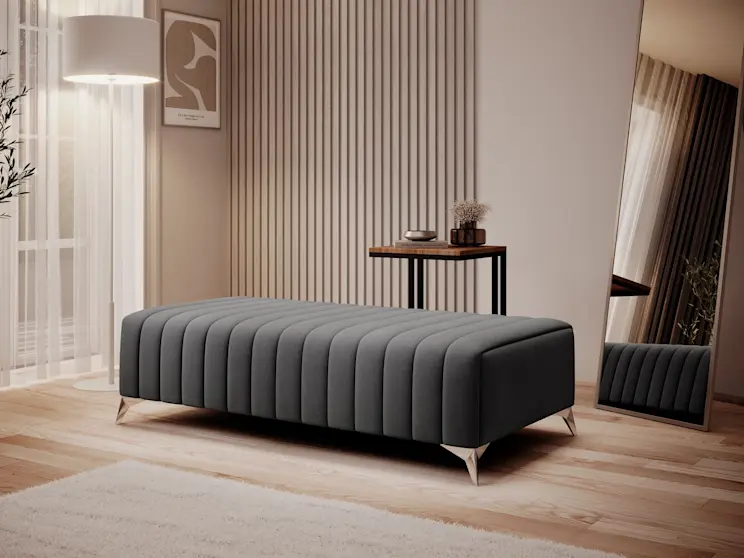 Stylowa pufa Laurence na metalowych nogach w towarzystwie lampy Vespillo, lustra Verona i stolika Vigo, w przytulnej, jasnej przestrzeni.