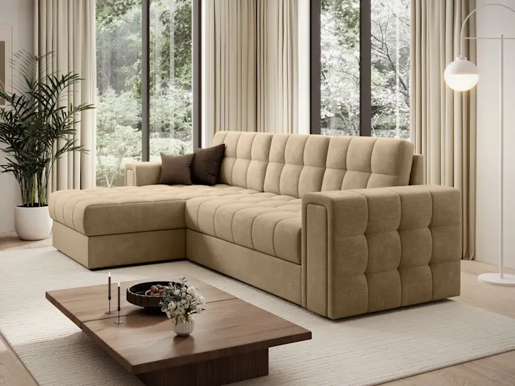 Nowoczesna aranżacja salonu z narożnikiem Blenvi Monolith 09 w ciepłym, beżowym odcieniu. Mebel ma głębokie siedziska i przeszycia, a całość uzupełnia jasny dywan, drewniany stolik oraz przytulne dodatki.