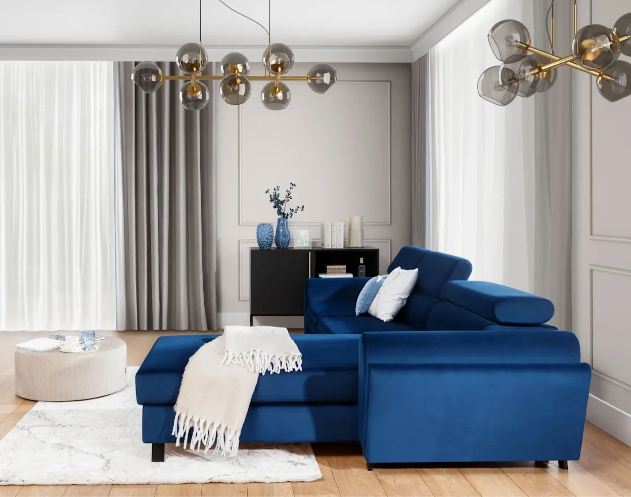 Nowoczesny salon z narożnikiem Mariall w głębokim, granatowym kolorze. W tle jasne ściany z listwami, długie zasłony i złote lampy sufitowe, a na szezlongu leży jasny pled i dekoracyjne poduszki.