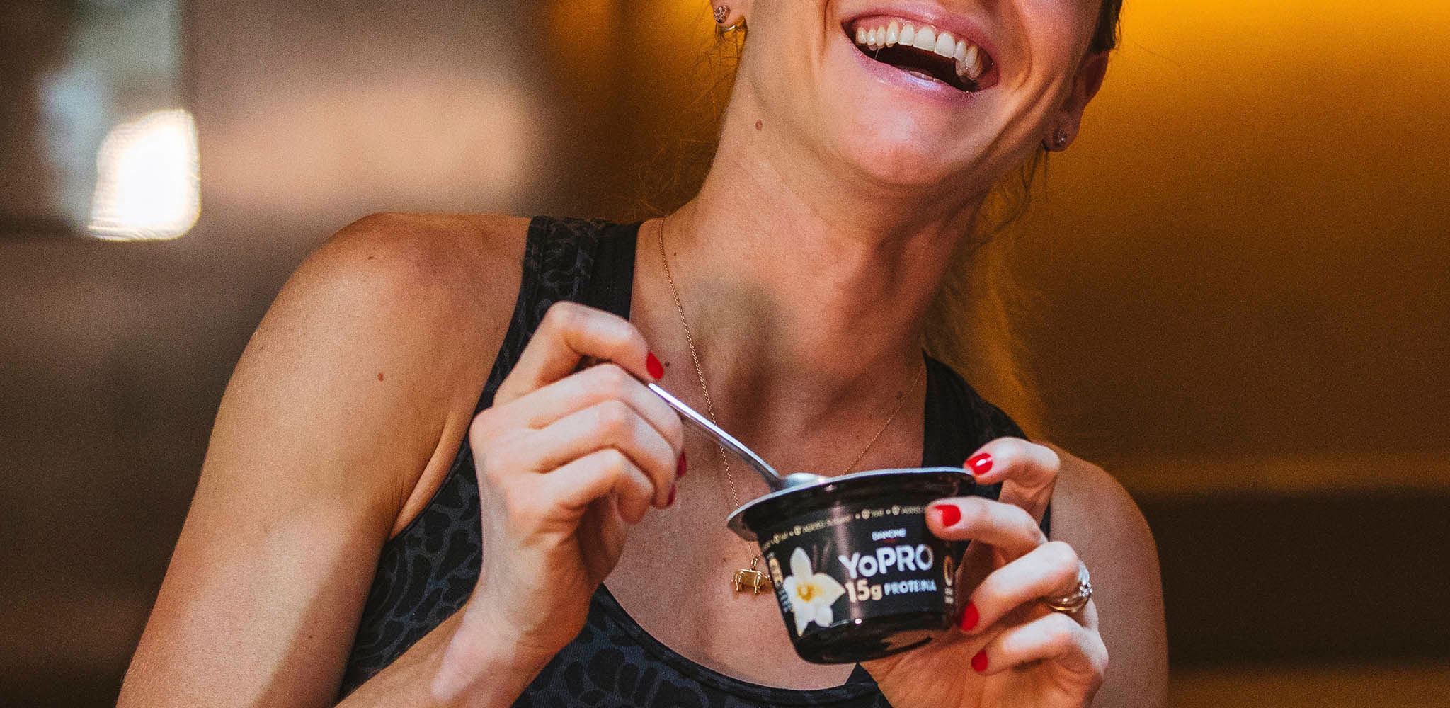 Mulher sorri segurando um YoPRO colherável