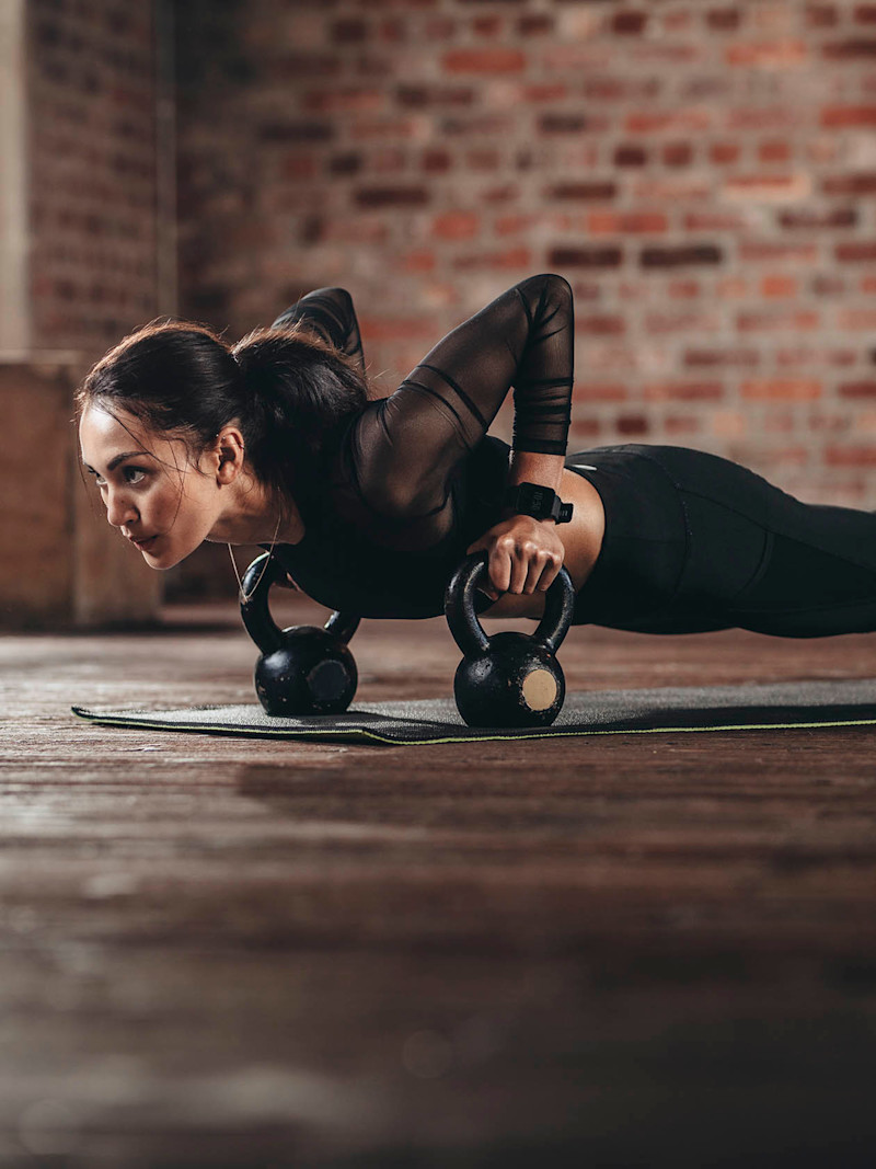 Mulher fazendo flexão usando um apoio de braços