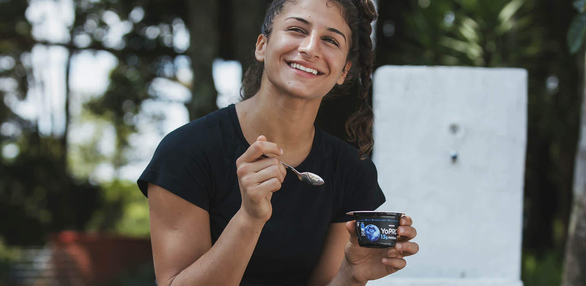 Mulher ri enquanto consome YoPRO colherável