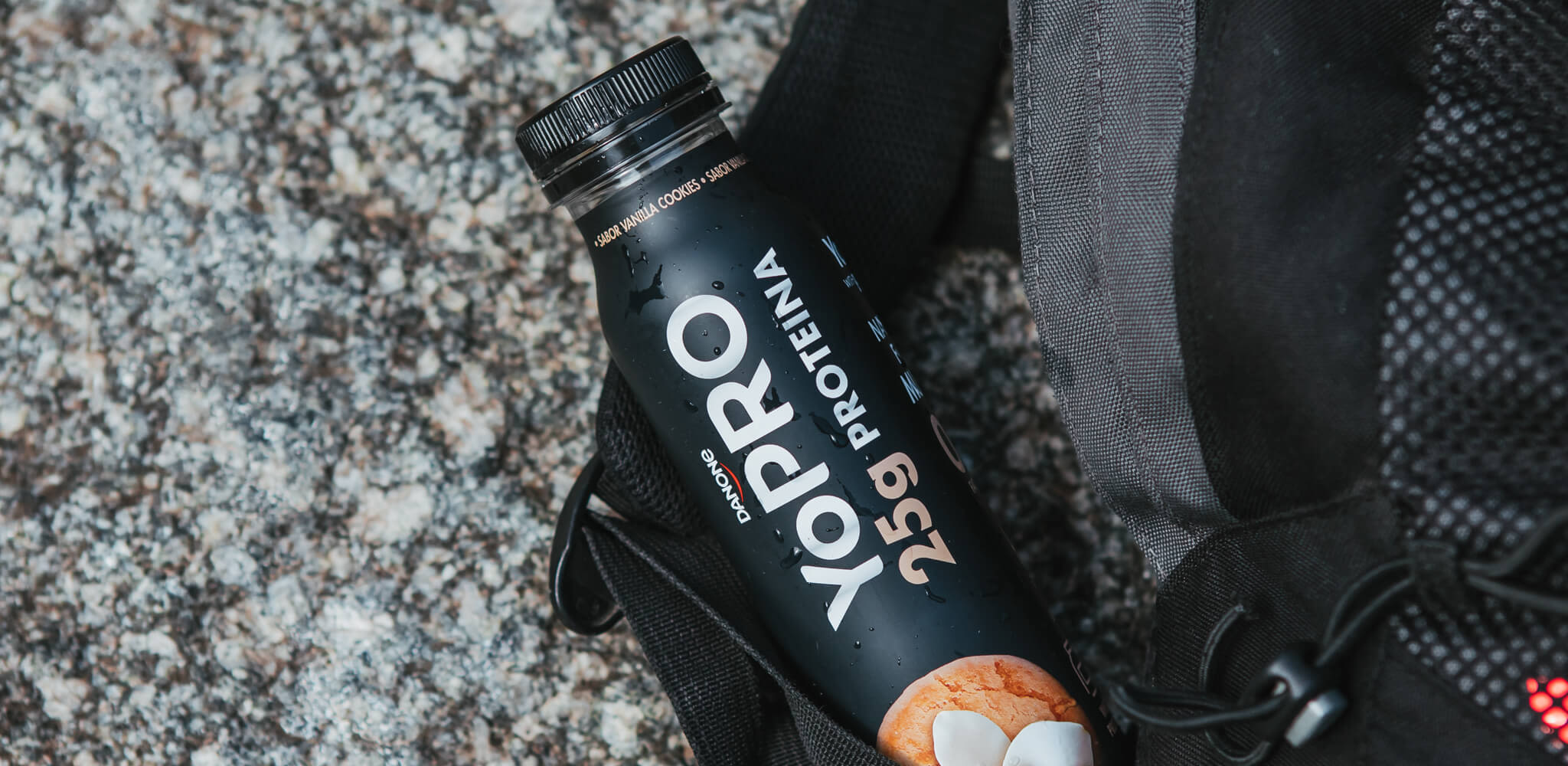 Bebida YoPRO no chão ao lado de uma mochila