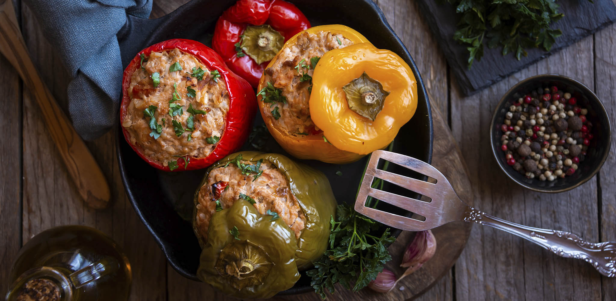 três pimentoes recheados com carne: um verde, um amarelo e um vermelho 
