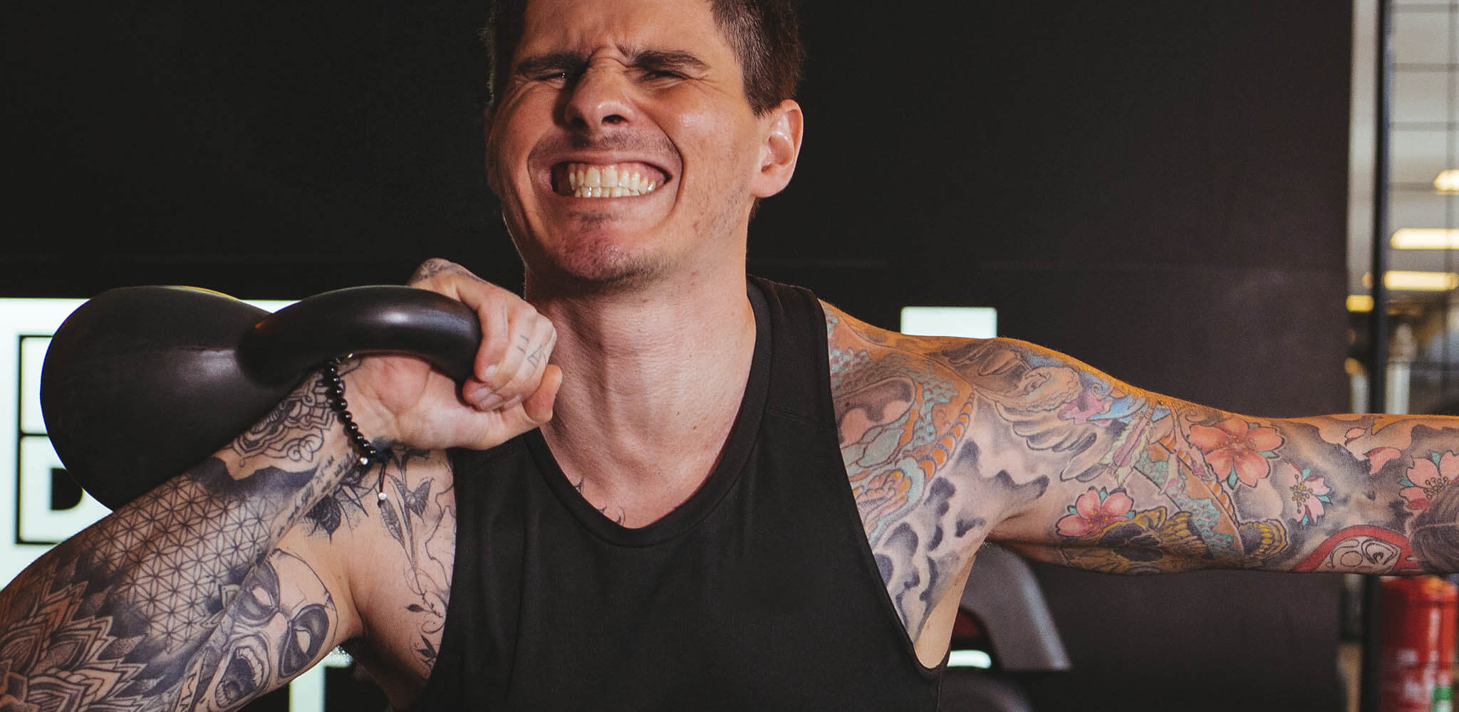 Homem faz força para sustentar peso em treino de musculação