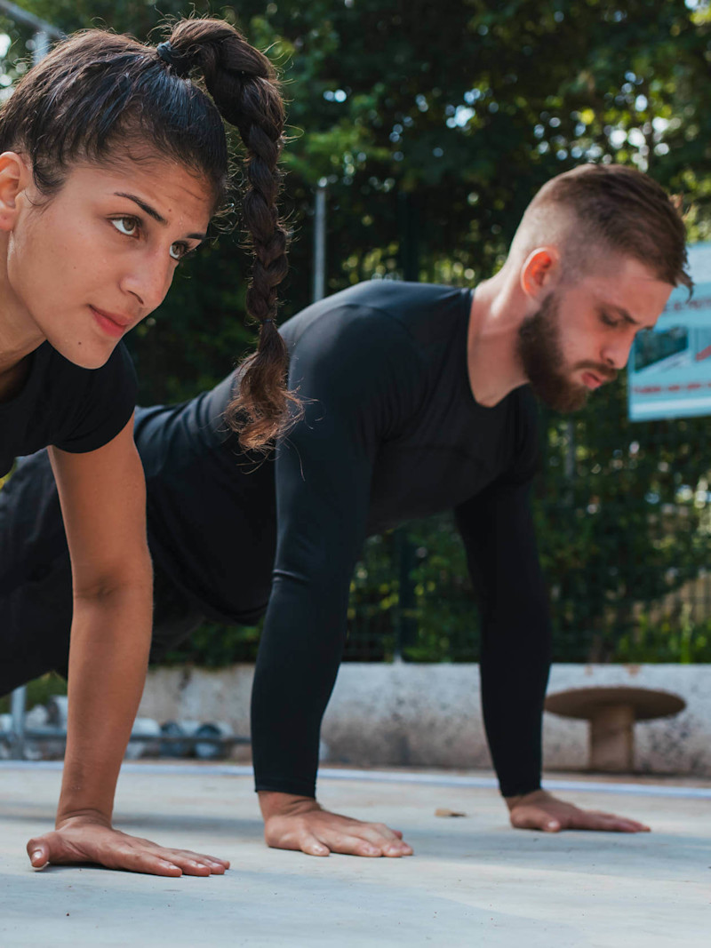 Mulher e homem fazem flexão