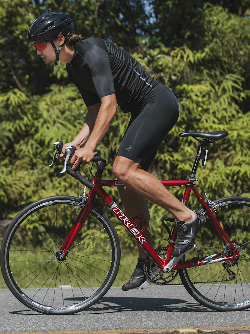 Ciclista pedala cercado de área verde