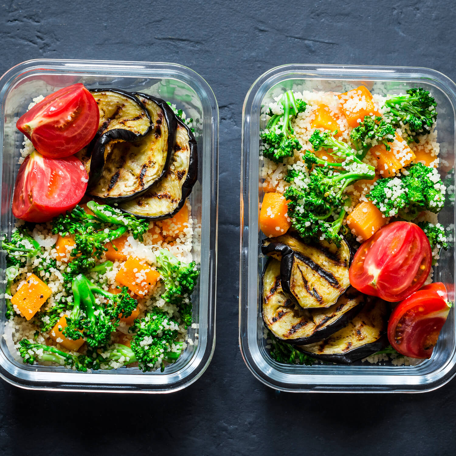 Duas vasilhas de vidro com legumes variados, como cenoura, brócolis, tomate e berinjela