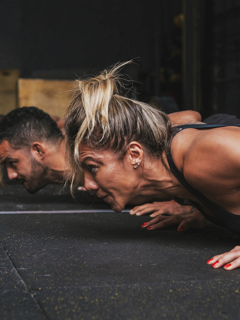 Homem e mulher fazem burpee em academia