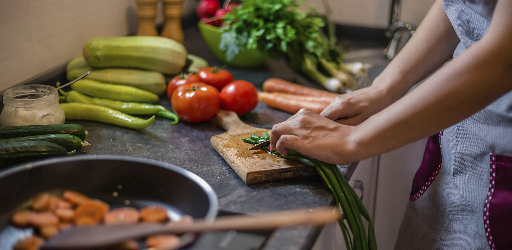Mulher corta legumes para levá-los ao fogo