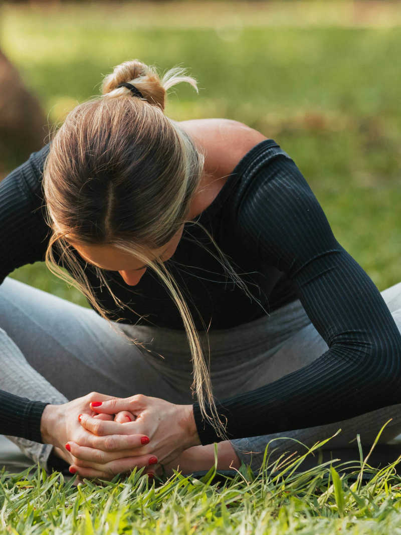 Mulher faz exercício de alongamento em parque