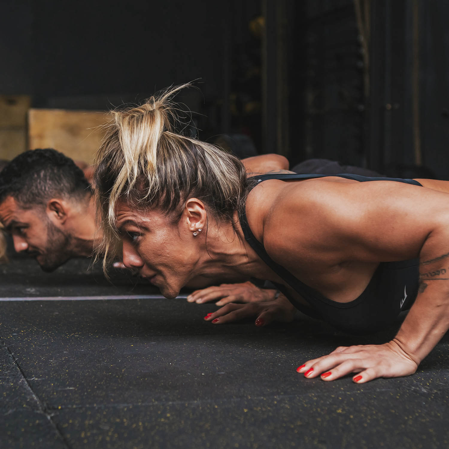 Homem e mulher fazem burpee em academia