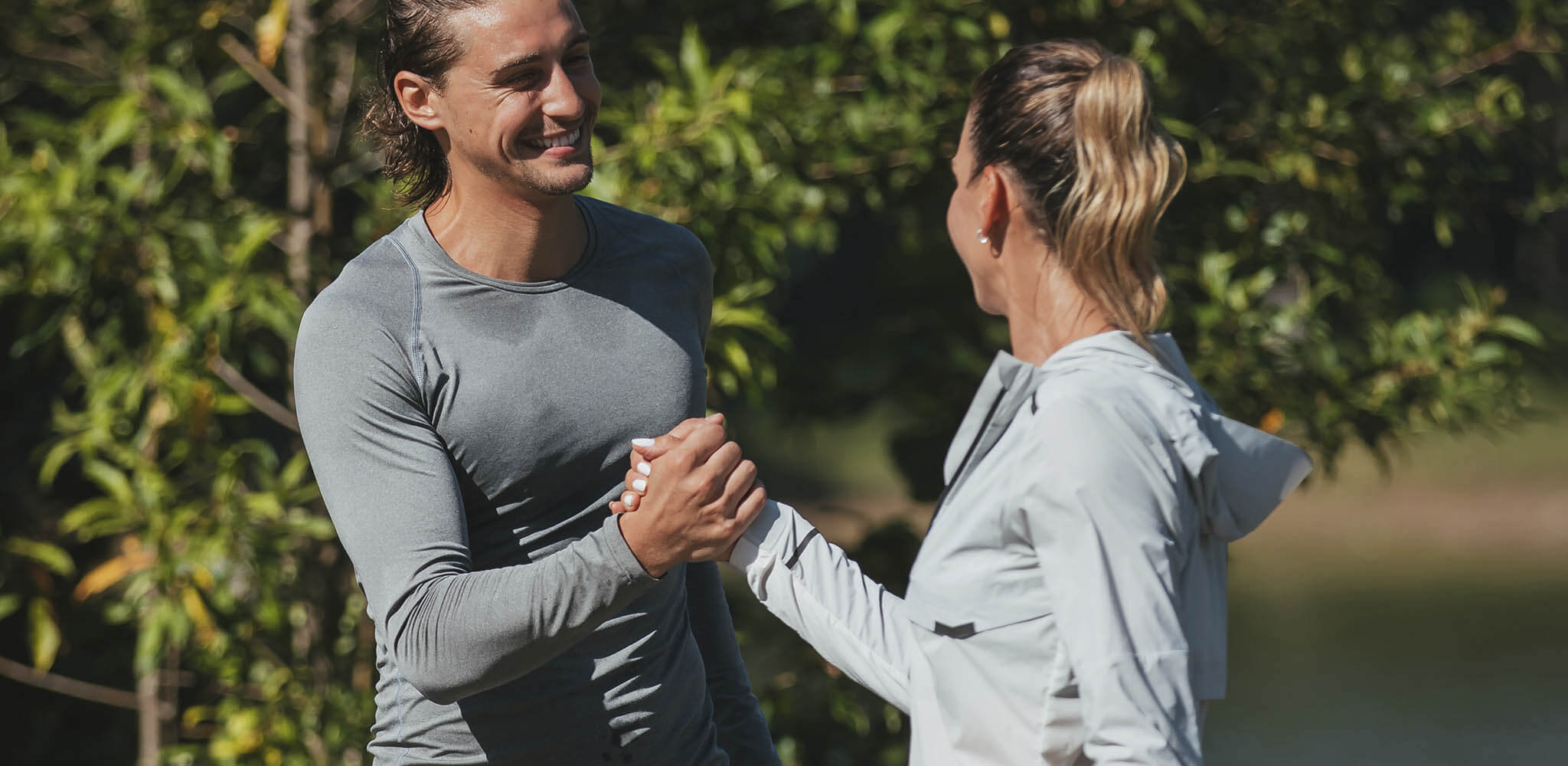 Homem e mulher se cumprimentam em treinamento ao ar livre