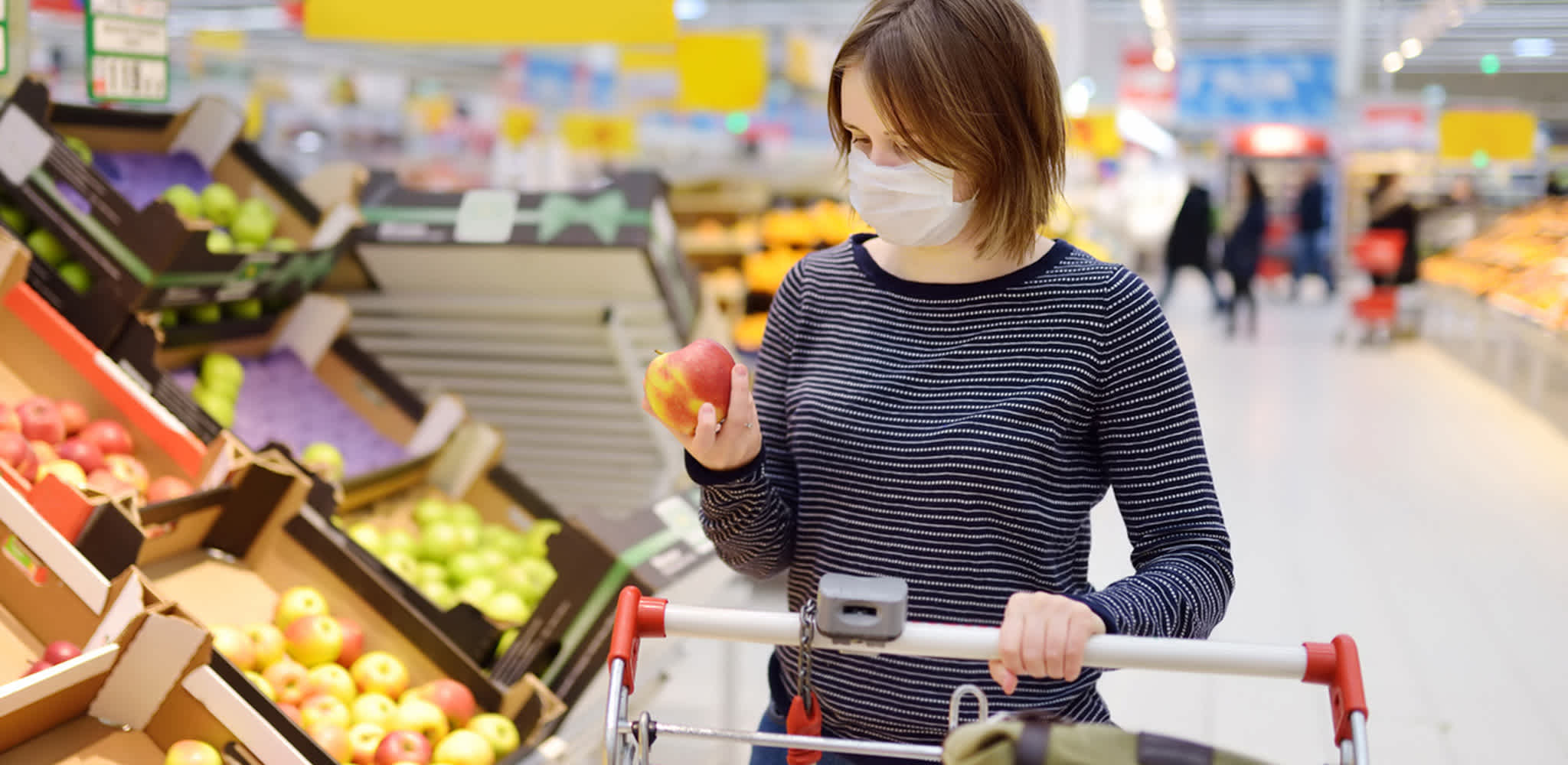 Mulher escolhe maçã em supermercado