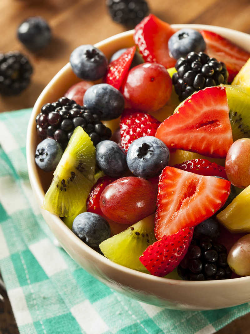 Salada de frutas em um pote sobre mesa com toalha xadrez