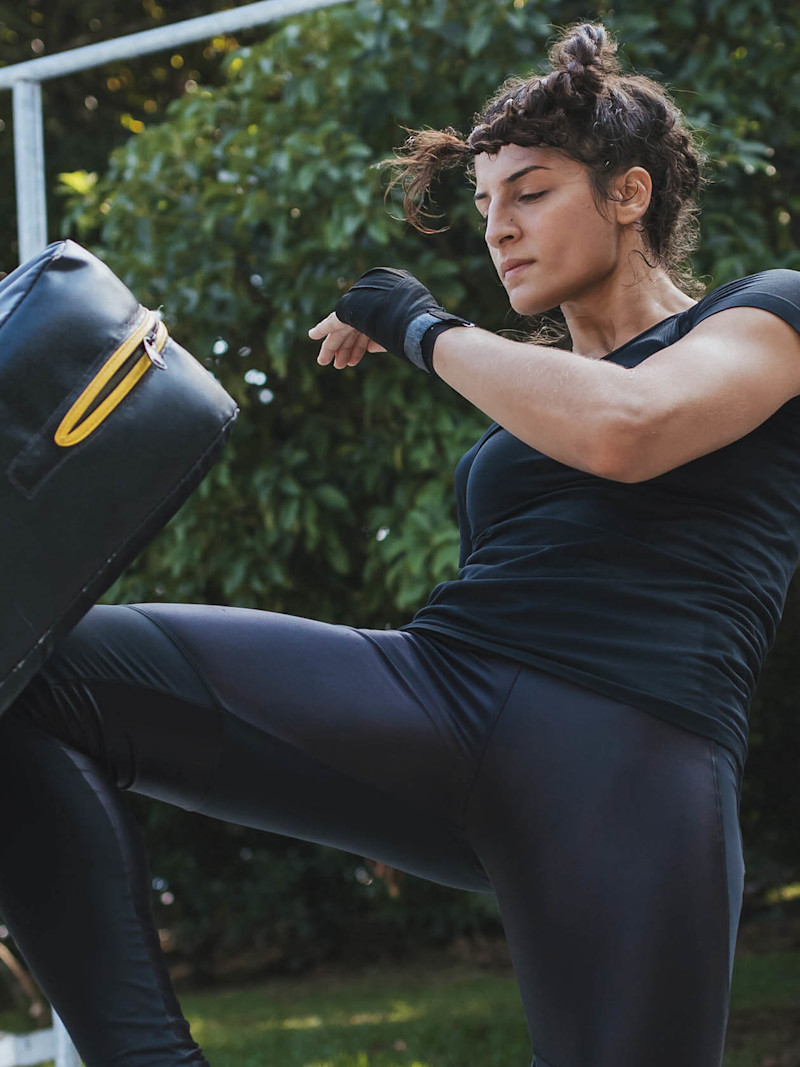 Mulher chutando peso em prática de kickboxing