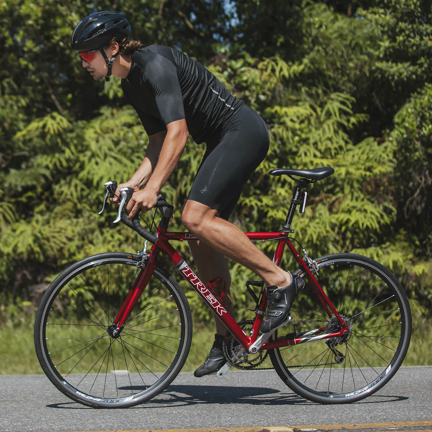 Ciclista pedala cercado de área verde