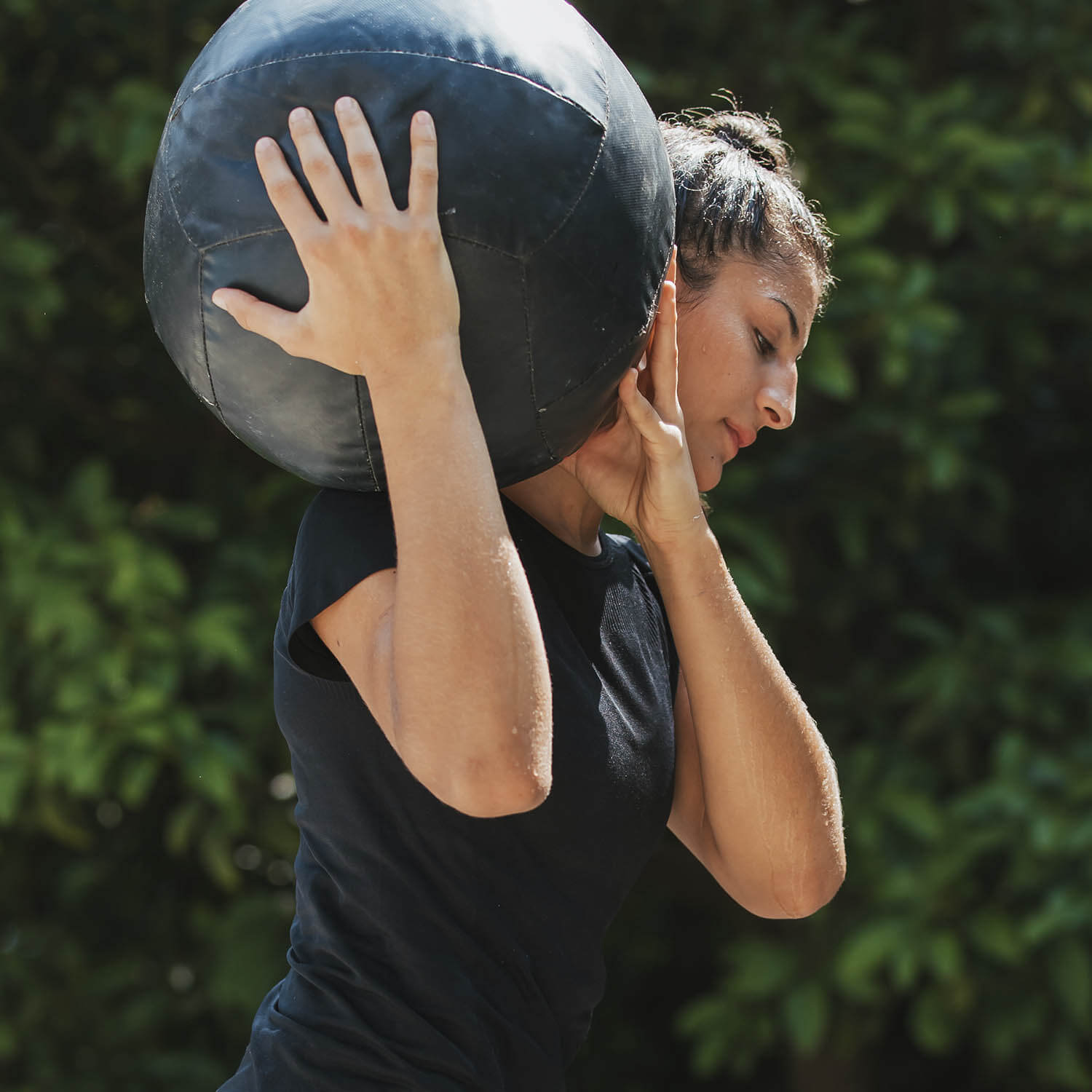 Mulher carrega bola no ombro direito durante treinamento