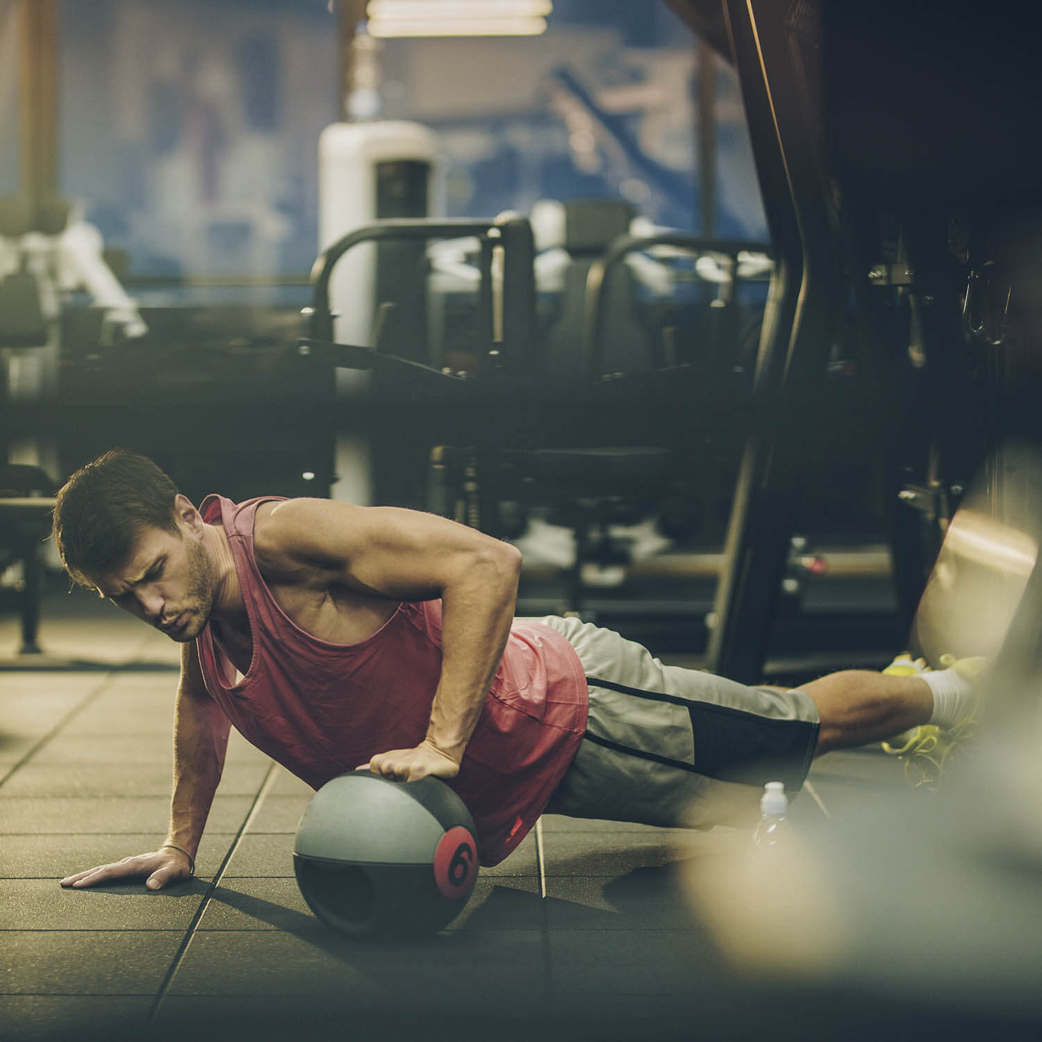 Homem faz exercício com bola em academia
