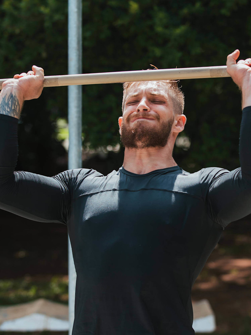 Homem levanta barra durante treino