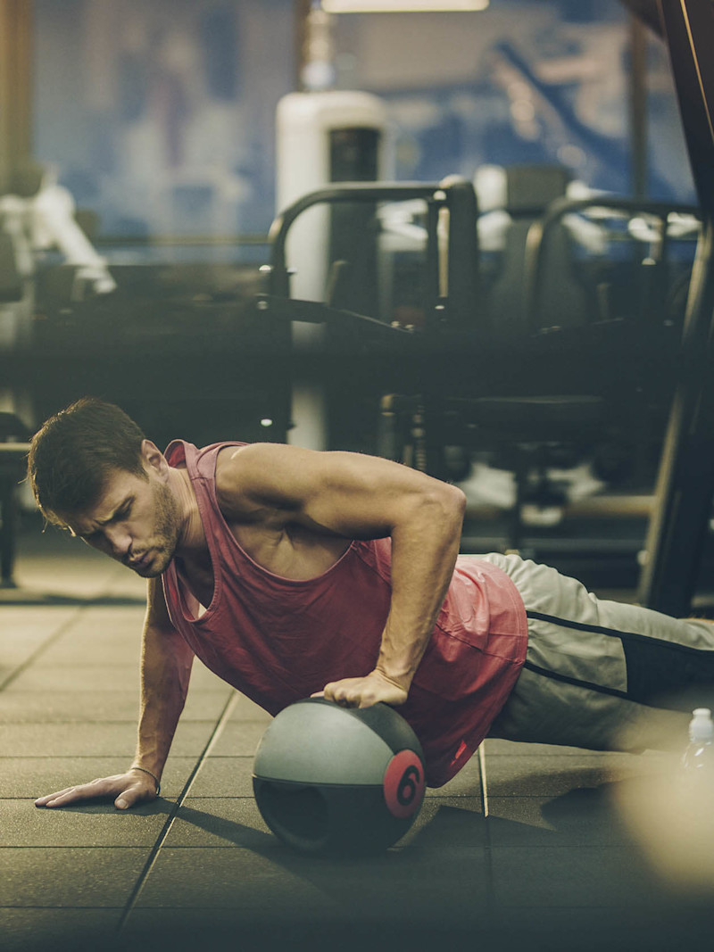 Homem faz exercício com bola em academia