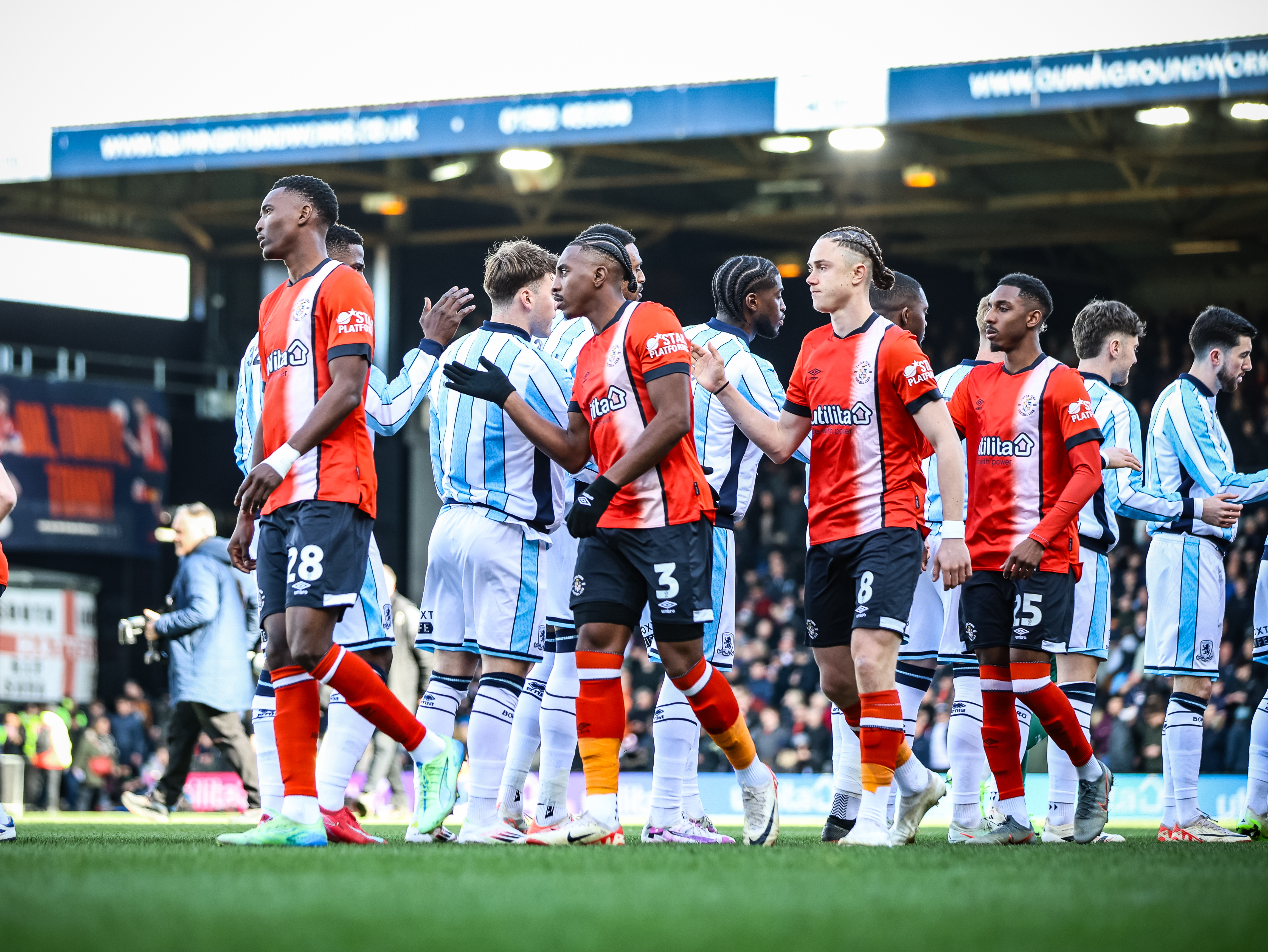 Amari'i Bell, Thelo Aasgaard and Izzy Jones shake hands with Middlesbrough players ahead of the game at Kenilworth Road.