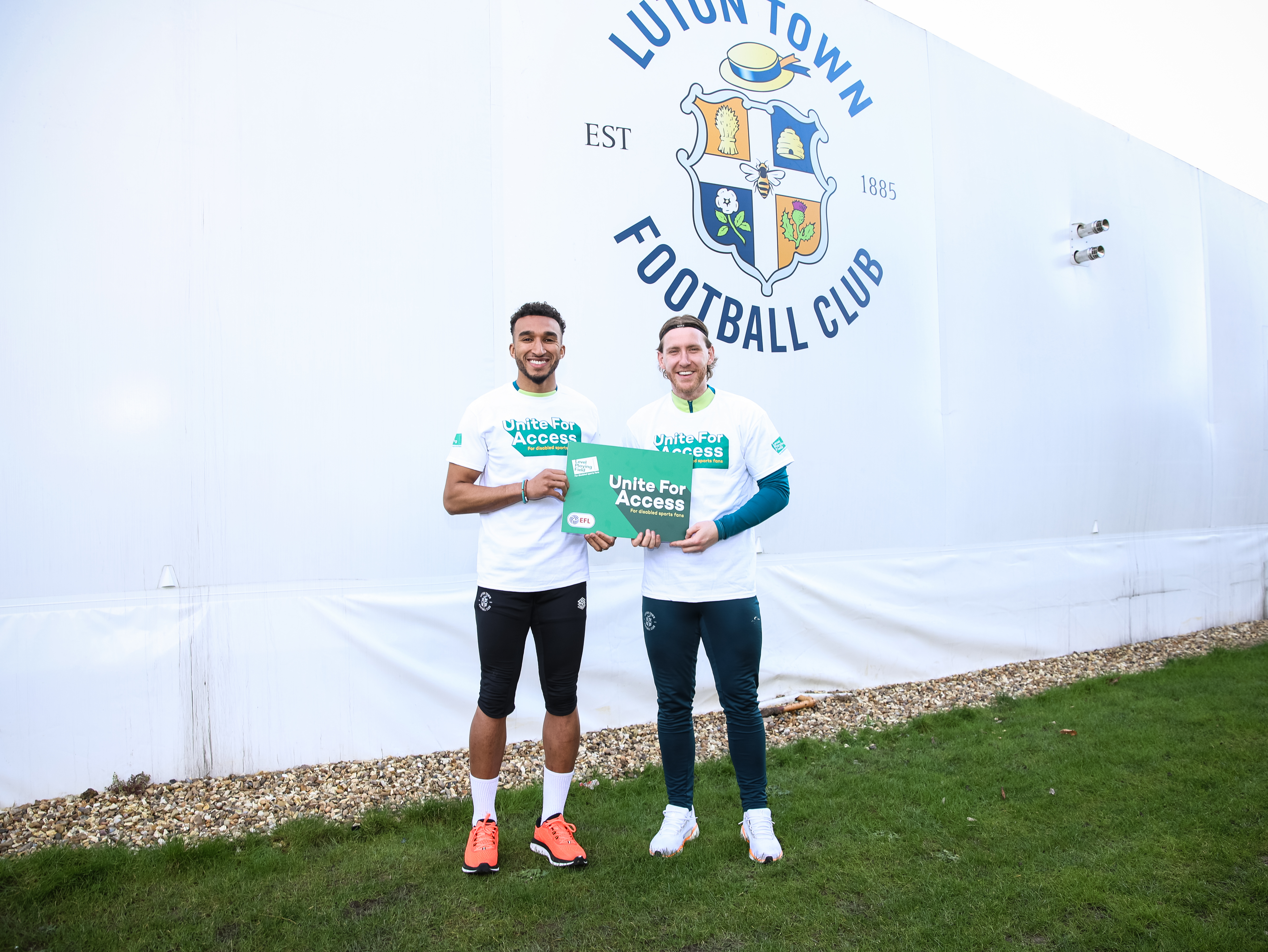 Jacob Brown and Josh Bowler stood outside the Performance Centre, holding a Unite For Access sign.