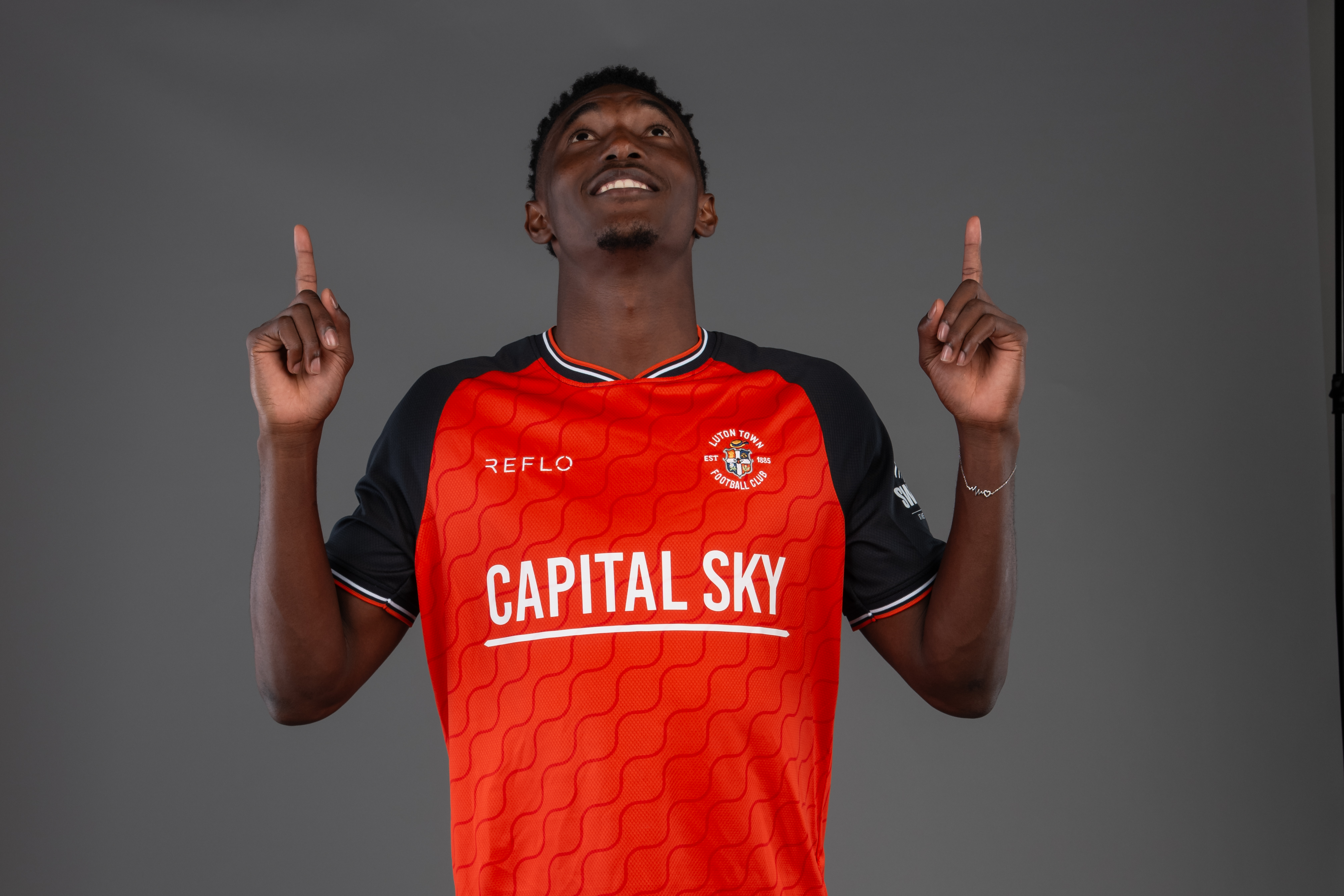 Christ Makosso shows off his goal celebration in front of a screen at the Luton Town content day.