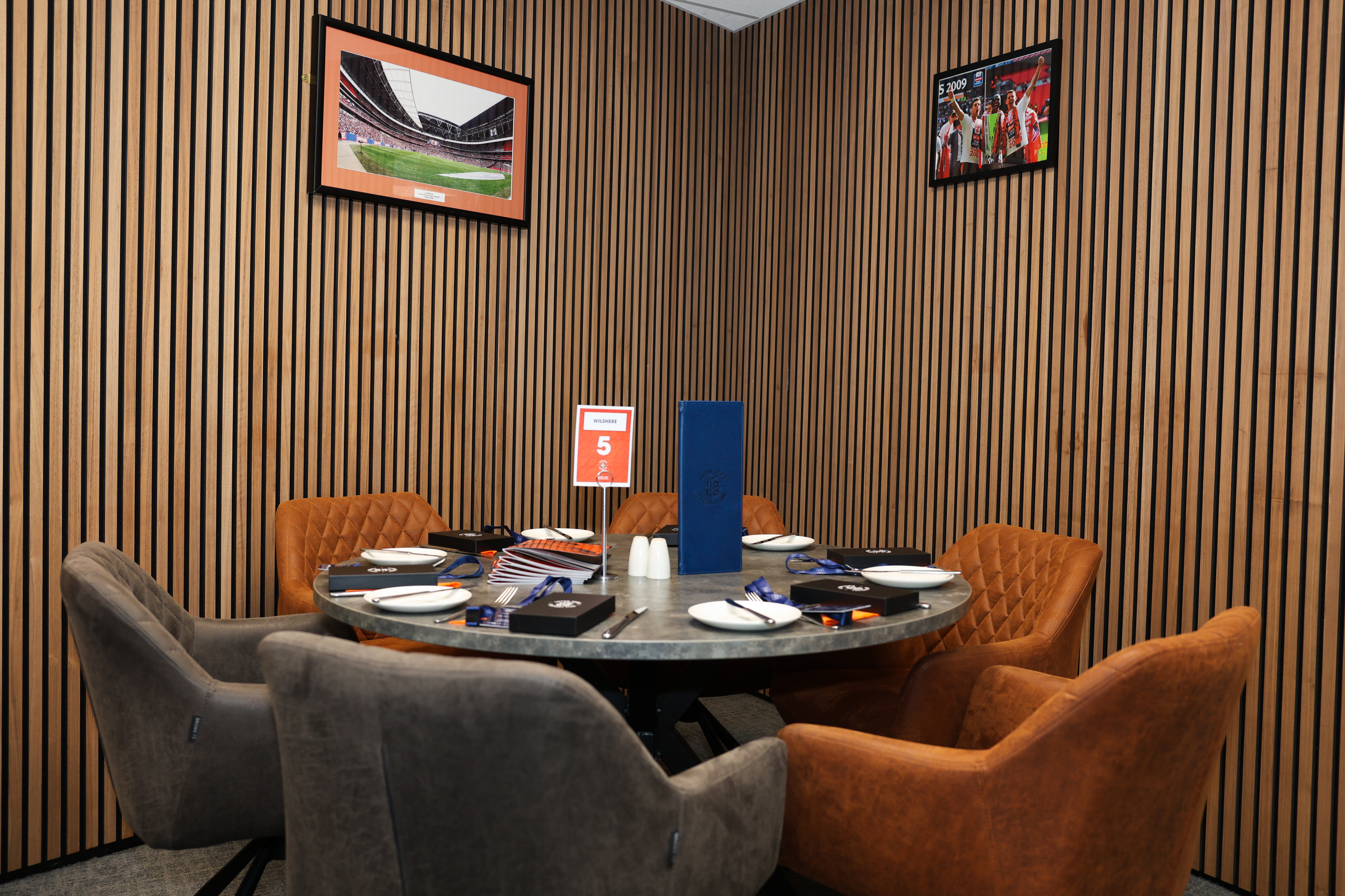 A table set up for hospitality in the Boot Room at Kenilworth Road, with pictures of Wembley and the Johnstone's Paint Trophy win in 2009 on the walls.