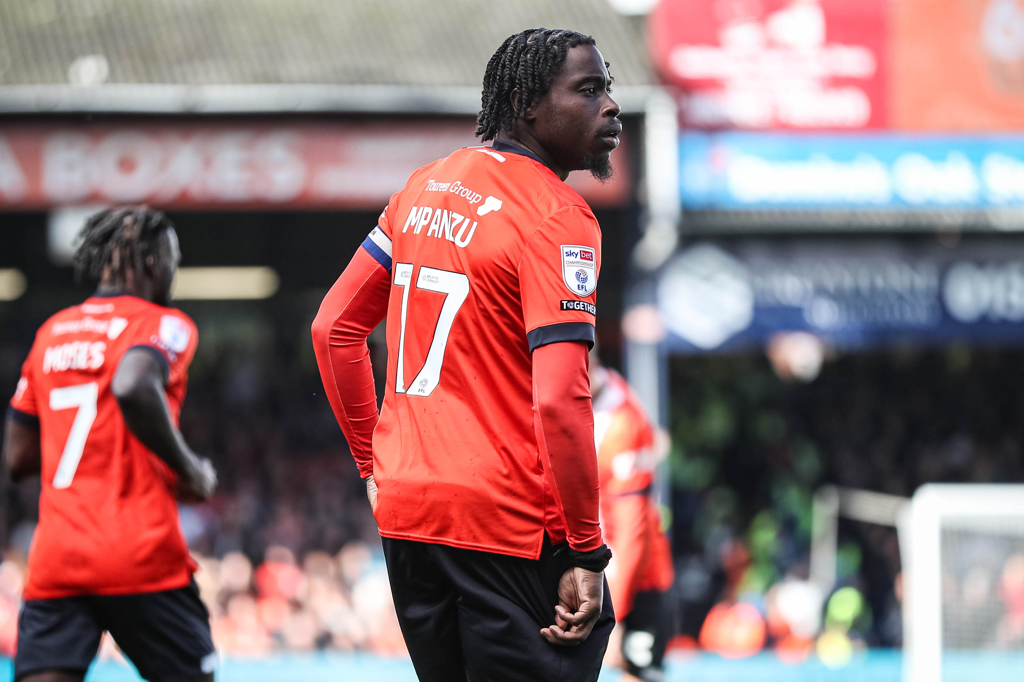 Pelly Ruddock Mpanzu, with the back of his number 17 shirt showing, while wearing the captain's armband at Kenilworth Road.