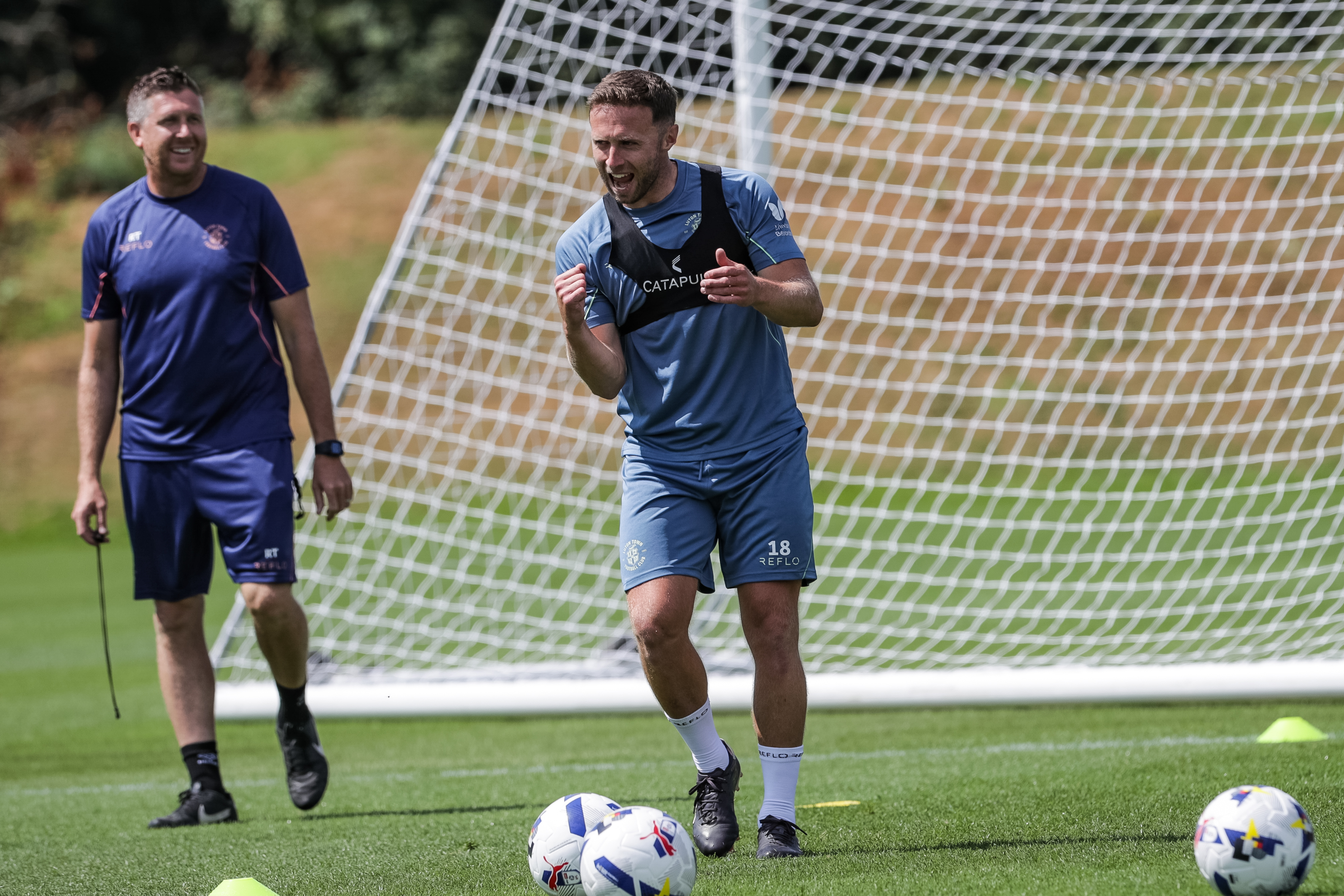 Jordan Clark is all smiles after scoring in training, with first team coach Richard Thomas smiling in the background too.