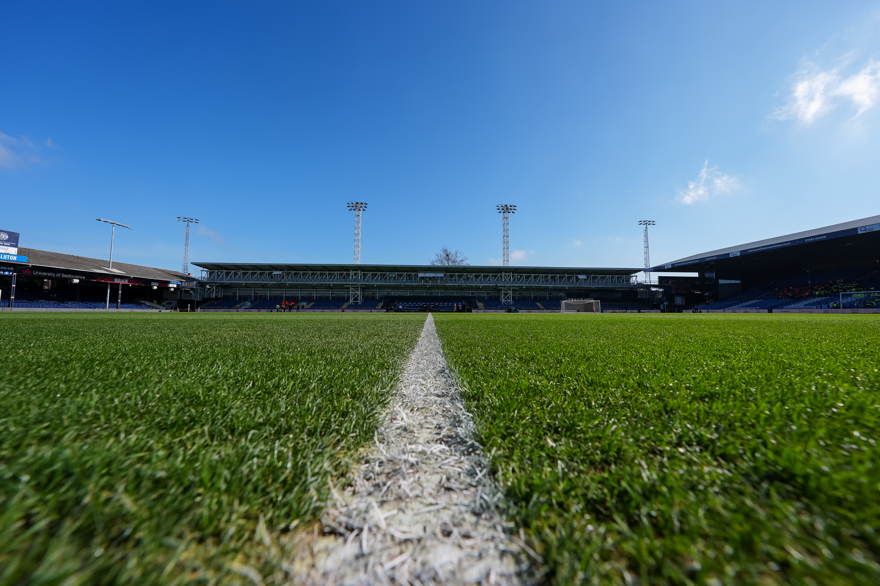 A view of the Bobbers Stand at Kenilworth Road from pitch level, with a clear blue sky above it.